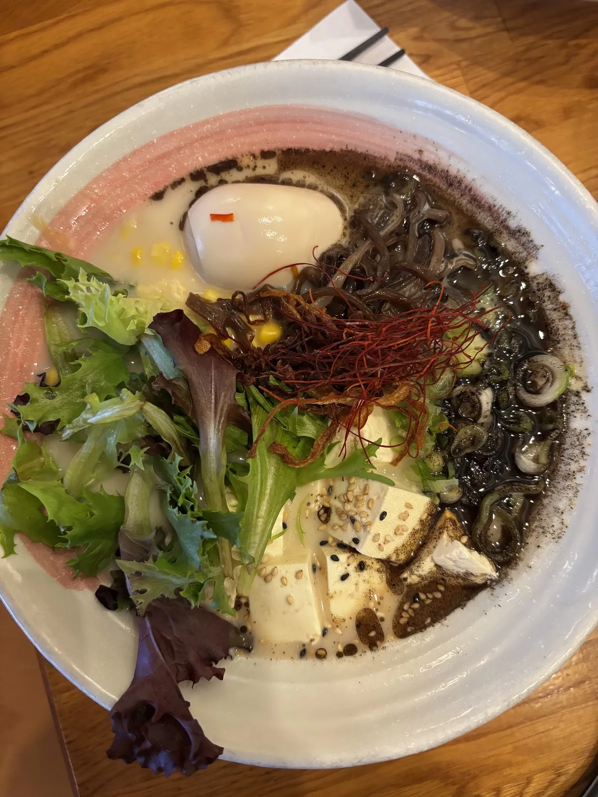 Overhead view of ramen with egg, tofu, and greens